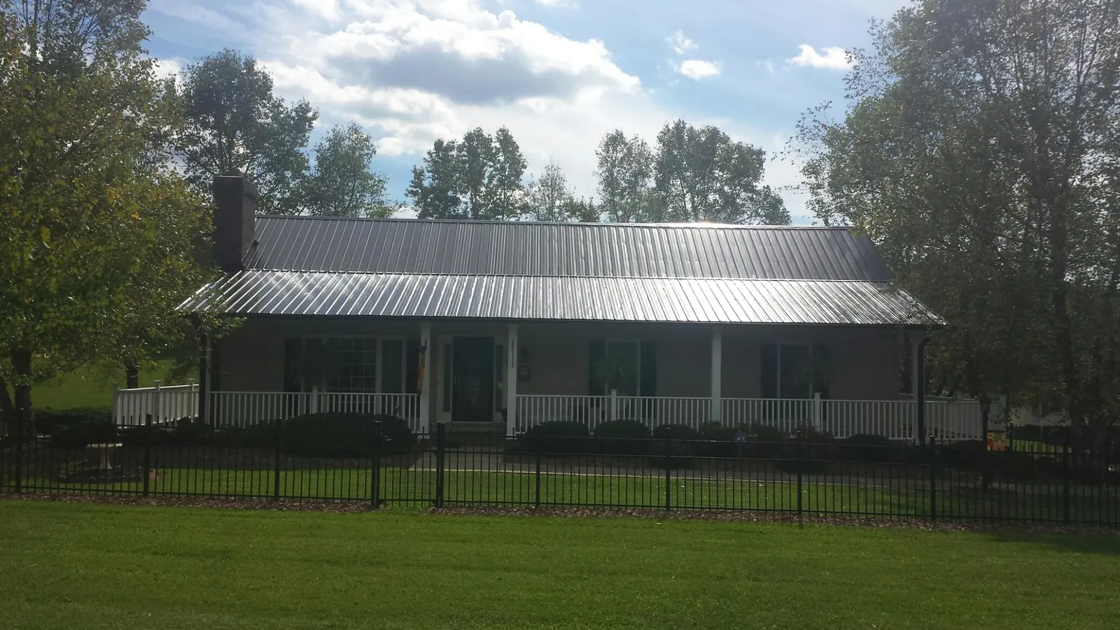 Gray metal roof on a brick ranch with a full width front porch — Gutter Guard Installation work by our crew in Dillsburg
