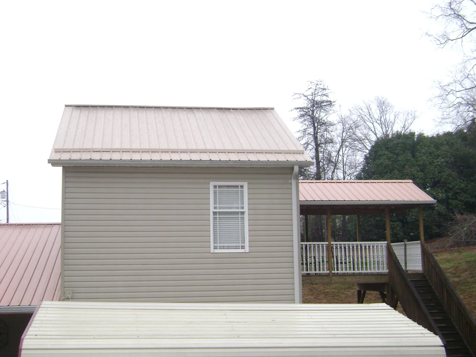 Tan metal roofs on a two story addition and attached porch, from a Roof Replacement job in Dillsburg