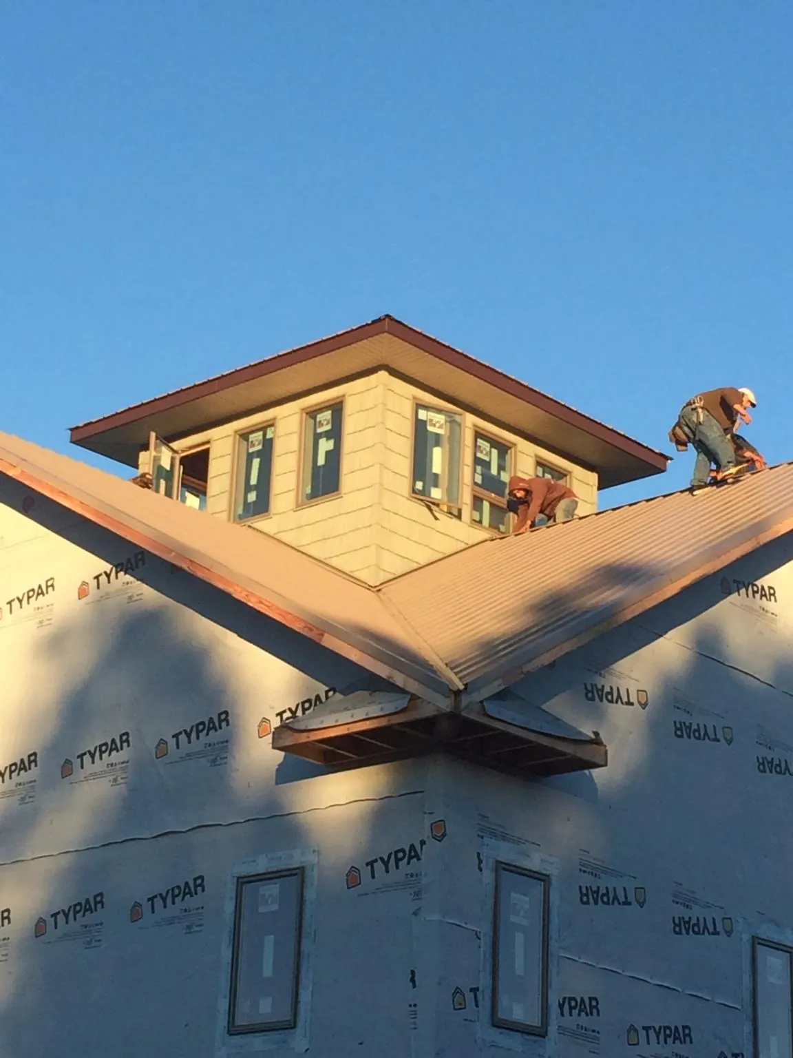 Roofers working around a rooftop cupola on a new metal roof at sunset — Roof Waterproofing in Dillsburg by Roofing Brothers